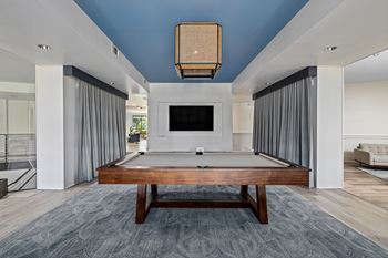 A modern living room with a pool table and a television.